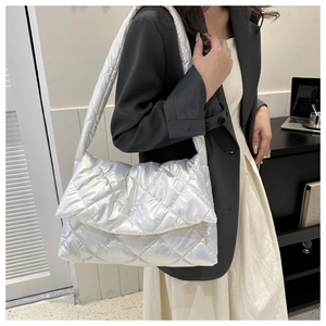 Silver quilted shoulder bag with glossy diamond pattern shown worn by a model in black