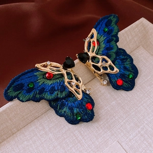 Macro shot of butterfly heart earrings with peacock feather embroidery and crystals