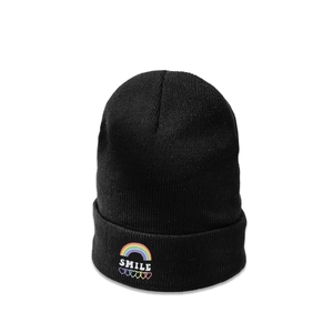Détail du bonnet en maille noire avec texte SMILE coloré et broderie de cœur arc-en-ciel