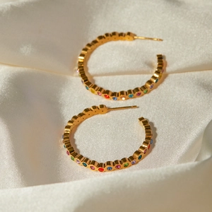 Vue détaillée des boucles d'oreilles en or 18k avec zircons colorés sur soie