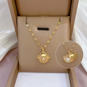 Hollow shell pendant necklace in gold with a white pearl, shown in luxury gift box