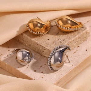 Close-up of geometric curved gold and silver earrings with micro-inlaid sparkling zircons