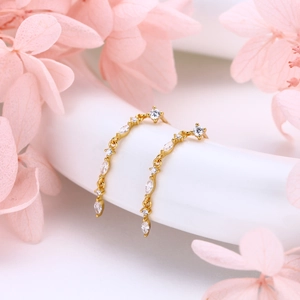 Elegant gold curved fringe earrings with marquise cubic zirconia on white base