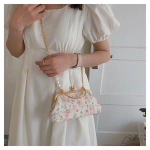 Detail of floral embroidery on a shell-shaped crossbody bag with pearl strap