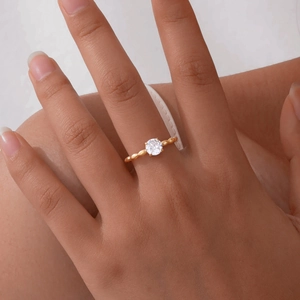 Detail of a gold Mobius ring with a single zircon on a finger, elegant twist design