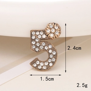 Macro view of a gold-toned vintage number five charm with white rhinestones and size details