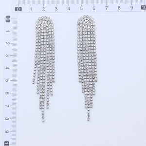 Detailed view of silver tassel rhinestone earrings showing length with a ruler tool