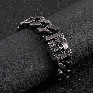 Detail of silver Cuban link bracelet with skull buckle on black textured background