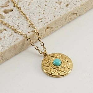 Macro view of golden stainless steel necklace with turquoise stone and star motif engraving