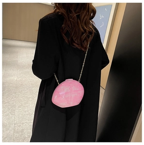 Rear view of pink shell-textured acrylic bag with a golden chain strap on a model