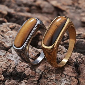 Macro view of gold and silver tiger eye stone rings on natural bark background