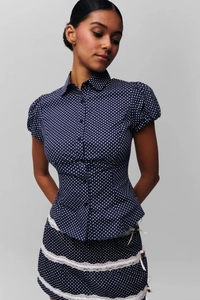 Detail of navy polka dot shirt with puff sleeves and lace trim on the matching skirt