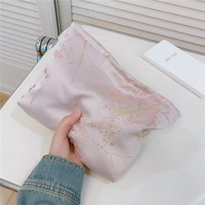 Détail de la trousse de toilette en satin rose avec motifs jacquard de fleurs de cerisier