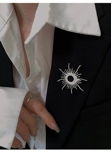 Close-up of a silver sunburst brooch with zircons on a black blazer lapel