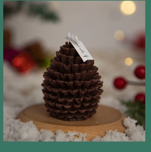 Macro detail of a pinecone scented candle on a wood base with festive snowy accents