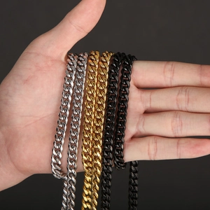 Close-up of classic Cuban link chains in silver, gold, and black finishes on a hand