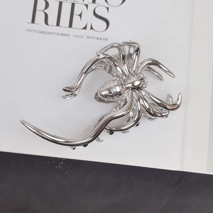 Detailed view of a silver spider claw clip on a minimalist white book background