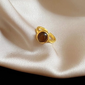 Detailansicht eines Vintage-Goldrings mit rundem braunem Tigerauge-Stein auf Seide