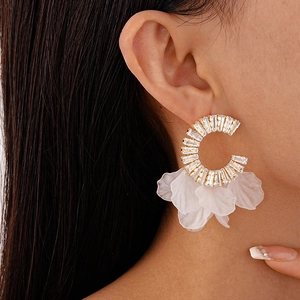 Detail of C-shaped earring with crystals and white flower petals worn on ear
