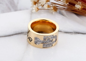Close-up of golden wide band ring with love engraving and bone-shaped zircon inlay