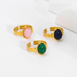 Dettaglio di tre anelli placcati in oro regolabili con pietre rosa, blu e verdi