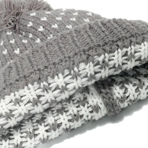 Grey knit beanie with white heart jacquard pattern and snowflake design and a fluffy pompom