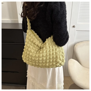 Detail of yellow puffy quilted bubble texture on minimalist crescent hobo tote shoulder bag