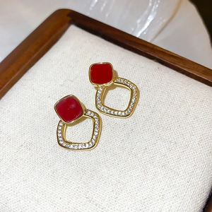 Gros plan détaillé de boucles d'oreilles dorées avec carré rouge et cristaux brillants