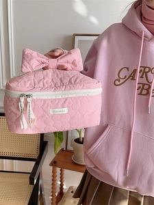 Trousse à maquillage rose matelassée avec motif floral et grande poignée nœud par mannequin