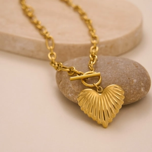 Detail of 18k gold plated heart pendant necklace with OT toggle clasp on marble stone