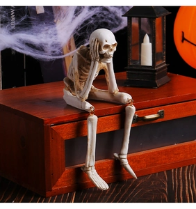 Halloween resin skeleton figurine sitting on a wooden box with spooky pumpkin lamp