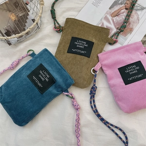 Close-up of corduroy crossbody phone bags in blue, green and pink with rope straps