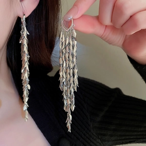 Detail of silver leaf fringe earrings with heart buckle shown on a model's ear