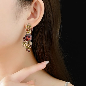 Detail of vintage gold leaf earrings with square red gemstone and multicolor crystals