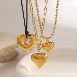 Three-piece gold heart pendant necklaces featuring varied chains on a minimalist stone base