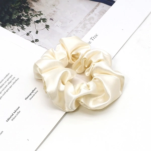 Detail of elegant champagne satin silk scrunchie placed on a magazine lifestyle background
