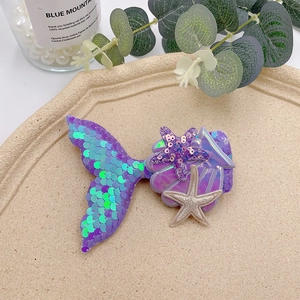 Detailed macro view of sequined mermaid tail, seashell, and starfish hair clips for girls