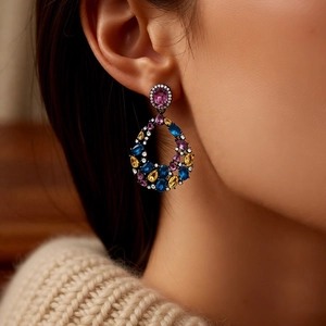 Close-up of model wearing colorful teardrop earrings with pink and blue stones