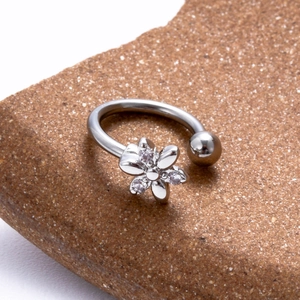 Vue détaillée d'un piercing en C argenté avec fleur en cristal sur une pierre naturelle