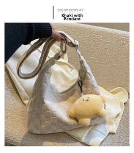 Close-up of khaki woven tote bag with a yellow star plush charm and wide shoulder strap