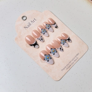 Détail de 10 faux ongles français avec fleurs bleues et pois noirs sur carte