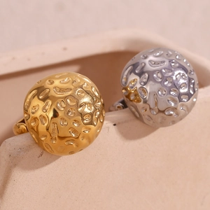 Gros plan de boucles d'oreilles boules dorées et argentées à texture martelée unique