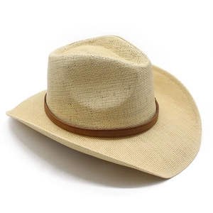 Detail of straw cowboy hat with natural weave texture and brown leather decorative band