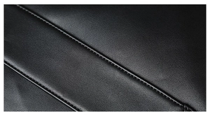 Close-up of black leather texture with detailed stitching on a punk style clutch bag