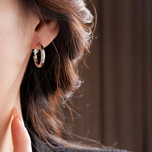 Close-up of minimalist silver hoop earring worn by a model with soft lighting