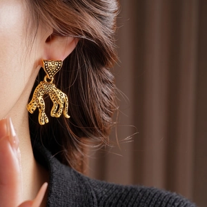 Vintage gold leopard drop earrings with embossed texture worn by a fashion model