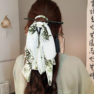 Detail of silk bow hair clip with bamboo pattern and long tassels on black hair stick