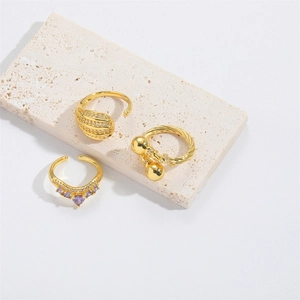 Three gold-toned teardrop adjustable open rings with purple and clear crystals