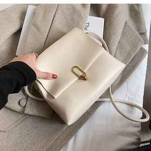 Détail du sac bandoulière crème avec élégant fermoir rotatif ovale doré en métal