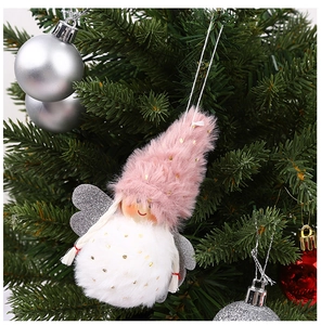 Detail of plush pink angel ornament with silver wings hanging on a Christmas tree